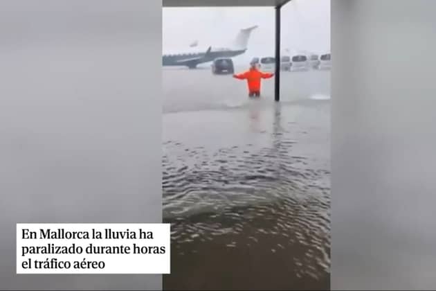 Man stands knee deep in water on runway at Majorca airport.