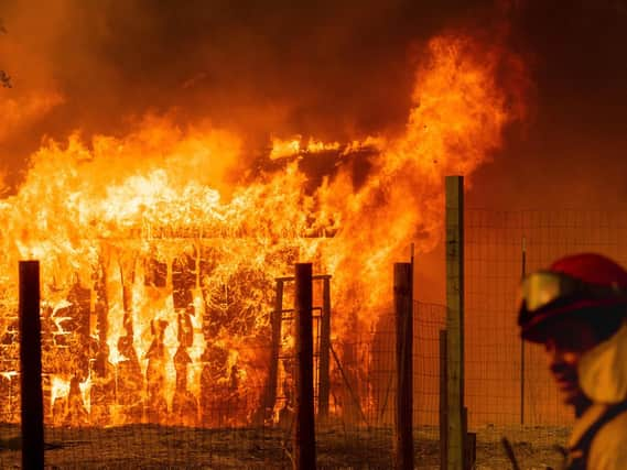 A firefighter monitors a burning outbuilding to ensure flames don't spread as the River Fire burns in Lakeport, Calif., on Monday, July 30, 2018. A pair of wildfires that prompted evacuation orders for nearly 20,000 people barreled Monday toward small lake towns in Northern California, and authorities faced questions about how quickly they warned residents about the wildfires. (AP Photo/Noah Berger)