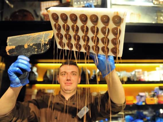 Chocolatier  Sam Flanagan   seen through the chocolate rain as he makes chocolates  at the York Chocolate Story  where a new exhibition 'Breaking The Mould :the Story of Kitkat'  is  being held.