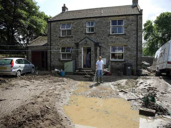 A man surveys the remains of his front garden in Reeth after flash floods destroyed it