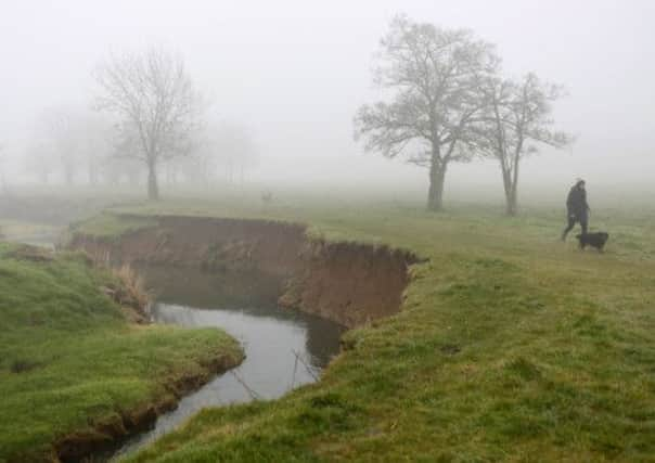 Fog shrouds dog walkers as they walk  beside Bourne Brook, in Toft Cambridgeshire.