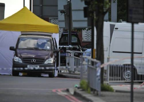 Police activity near a crashed car (rear) with a broken windscreen close to the scene where a man was murdered in John Wilson Street, Woolwich.