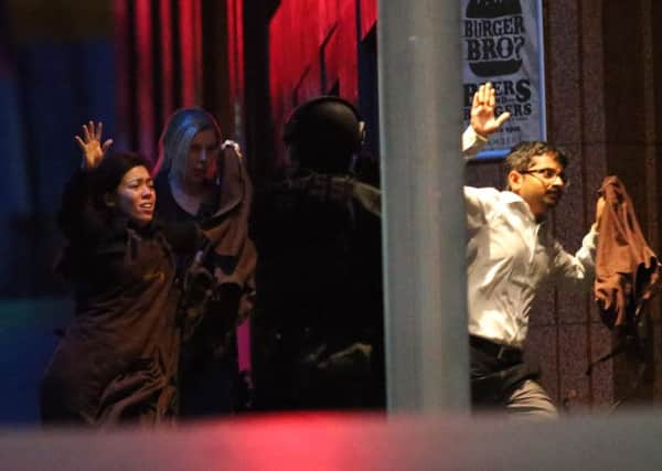 Hostages run towards armed tactical response police as they run to freedom from a cafe under siege in Sydney