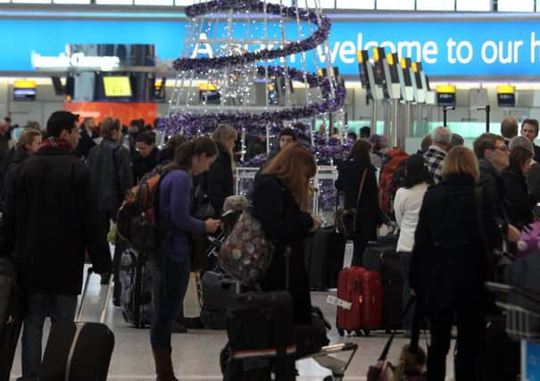 Passengers around the Christmas tree at Heathrow Airport