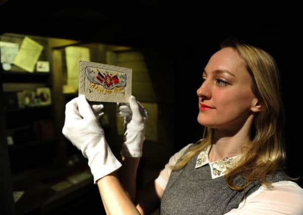 Helen Thornton of York's Castle Museum with a card sent to a loved one  from the front during World War 1