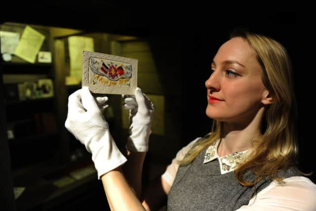 Helen Thornton of York's Castle Museum with a card sent to a loved one  from the front during World War 1