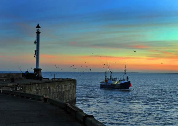 A fishing boat returns to Bridlington Harbour at dusk.