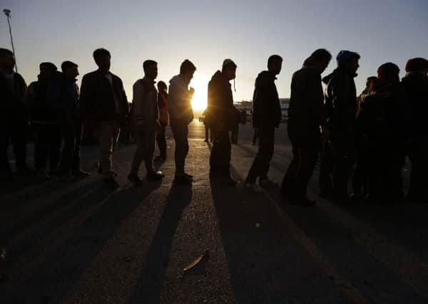 Refugees and migrants wait in a queue as the sun rises, to receive food distributed by non-governmental organisation after their arrival from the eastern Greek islands to the Athens port of Piraeus.