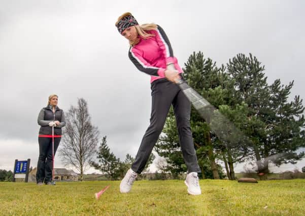 Helen Searle tees off under the watchful eye of Ellie Robinson.