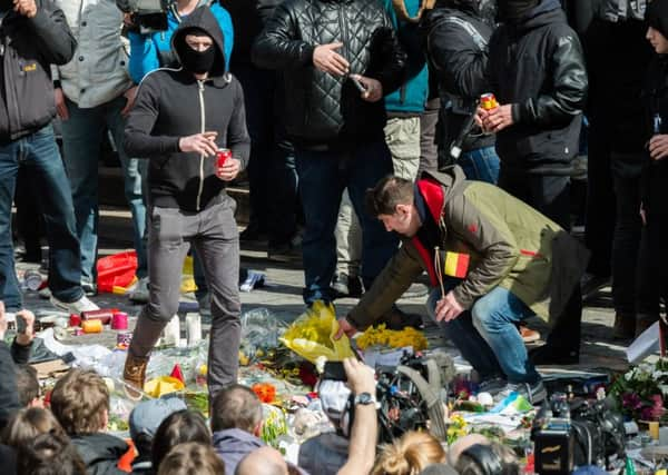 A right wing demonstrator walks on flowers as he protests at a memorial site at the Place de la Bourse in Brussels, Sunday, March 27, 2016.