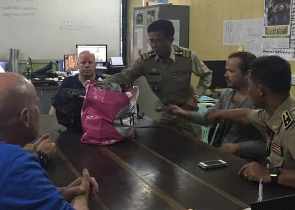 Damien Midgley (second from right) is handed over by Cambodian police