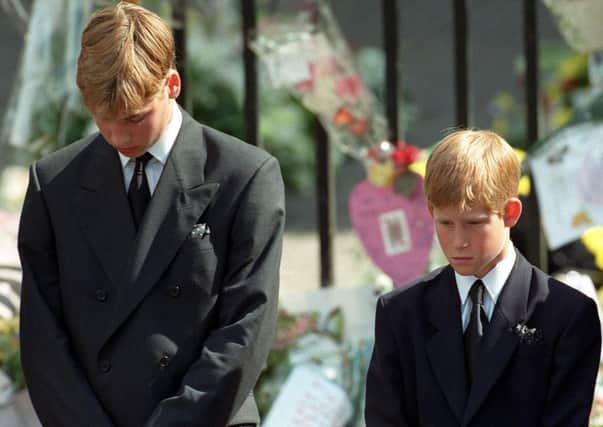 Princes William and Harry bow their heads at their mother's funeral in 1997.