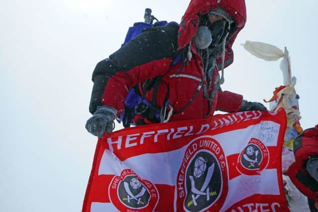 Ian Toothill, a Sheffield Wednesday fan, planting a Sheffield United flag to secure a Â£1,000 donation to Macmillan Cancer Support.