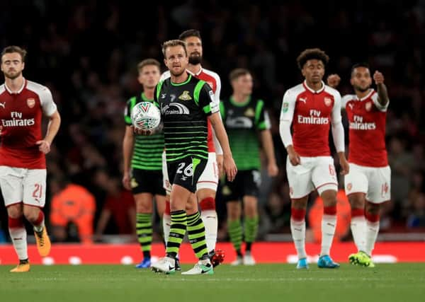 Doncaster Rovers' James Coppinger holds the ball to restart the match after Arsenal's Theo Walcott (right) scores his side's first goal of the game (Pictures: PA)