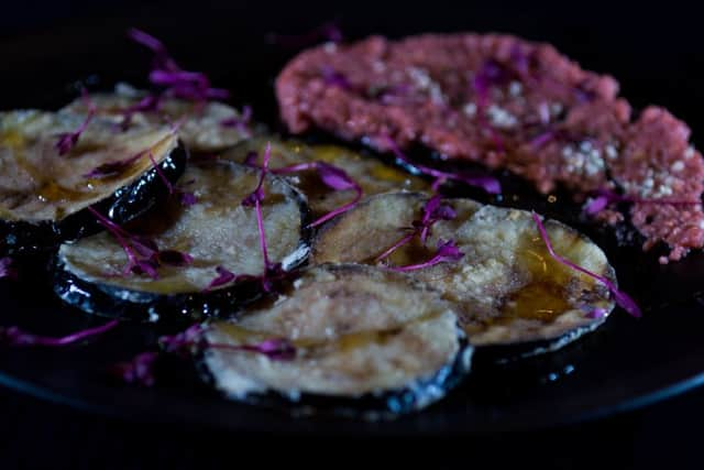 A beautiful dish of organic aubergine fritters finshed with maple syrup and hemp seeds, salad leaves, hummus.