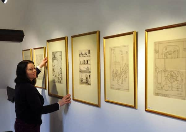 FUN WITH ART: Laura Farrell, from Nunnington Hall, hangs illustrations by William Heath Robinson. PIC: Bruce Rollinson