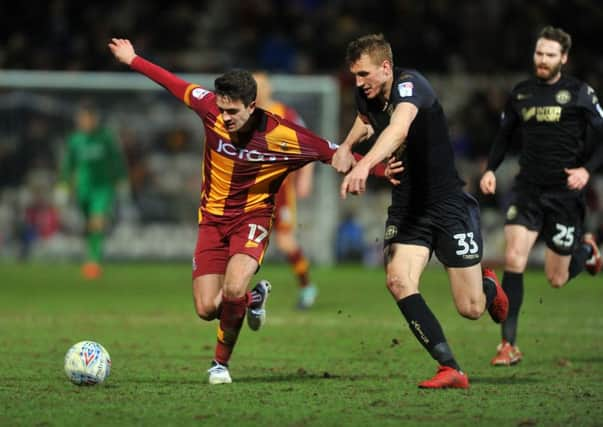 Bradford Citys Alex Gilliead is held back by Wigan Athletics Dan Burn during the League One encounter at Valley Parade (Picture: Tony Johnson).